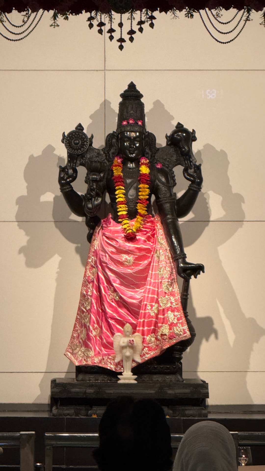 The black stone murti of Shri Hari at the Shri Hari Temple, garlanded with marigolds and dressed in pink silk