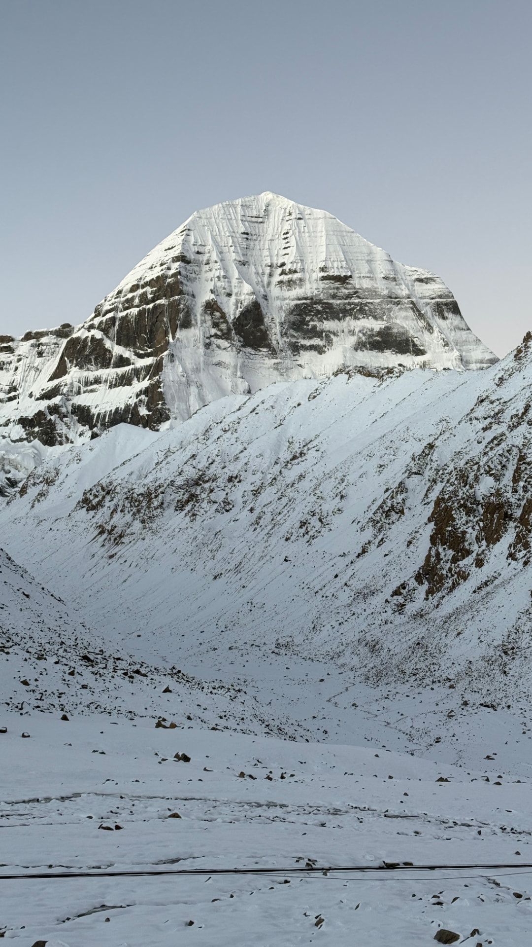 Mount Kailash rising above snow-covered ridges under a soft evening sky